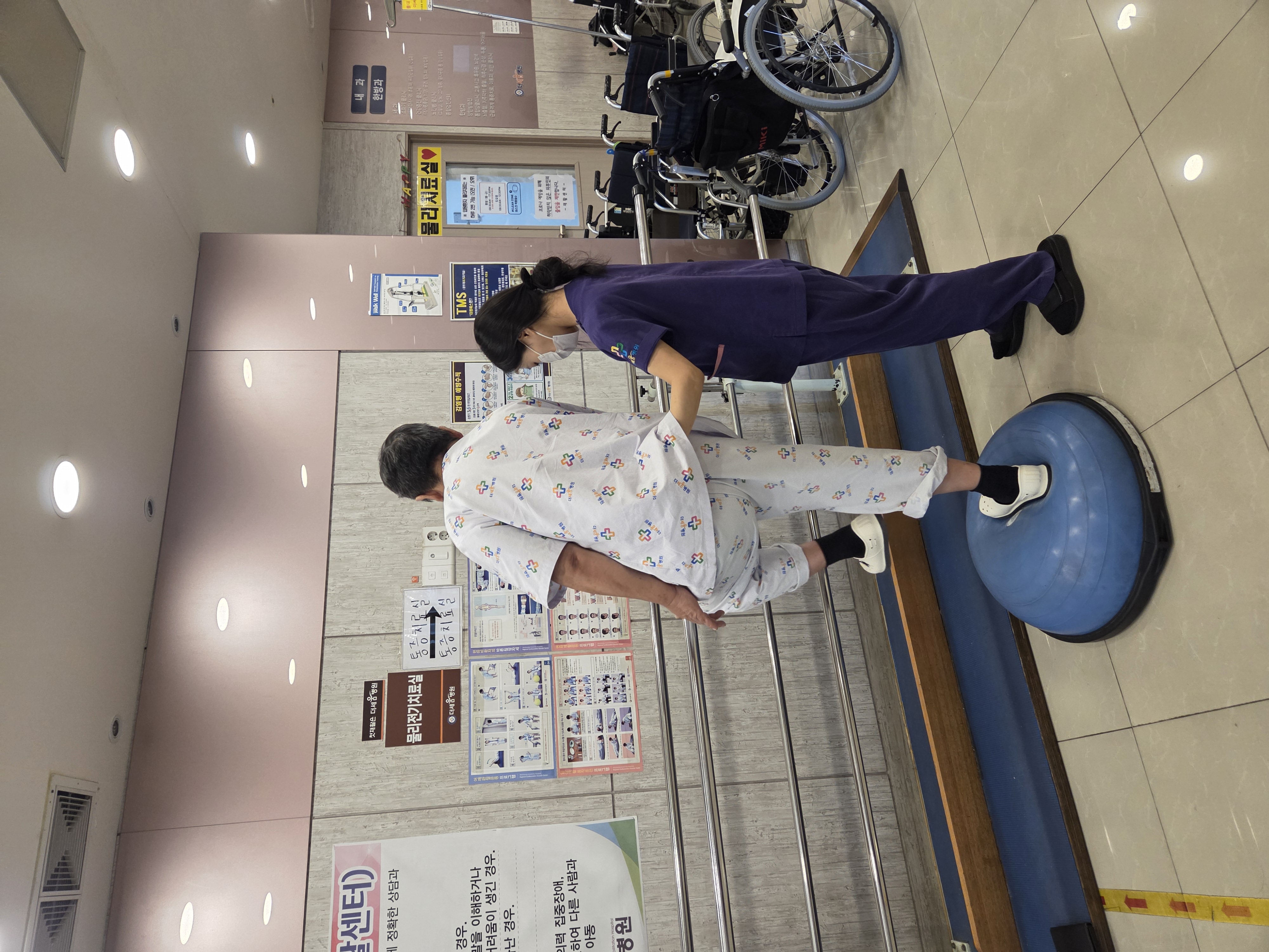 환자가 치료사와 함께 보행 훈련을 하는 뒷모습